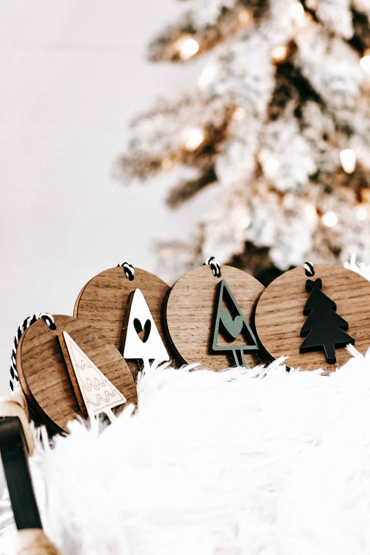Row of wooden Christmas ornaments with tree, heart, and angel shapes on striped string hangers