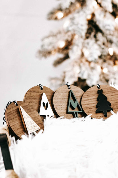 Row of wooden Christmas ornaments with tree, heart, and angel shapes on striped string hangers