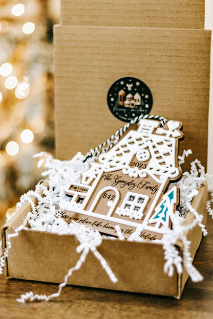 Wood gingerbread house ornament in snow on a kraft box, teal tree cutout, hanging loop