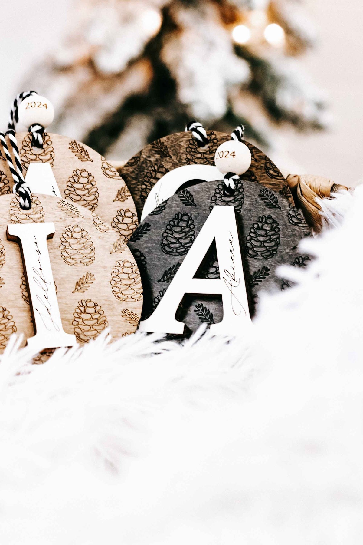 Round engraved pine cone ornament with letter A, zebra-striped cord, year 2024 tag