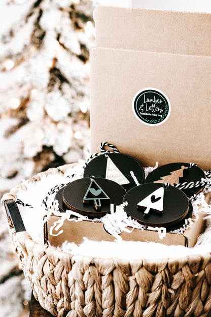 Kraft gift box with black round Christmas ornaments and twine hangers, tree and heart icons