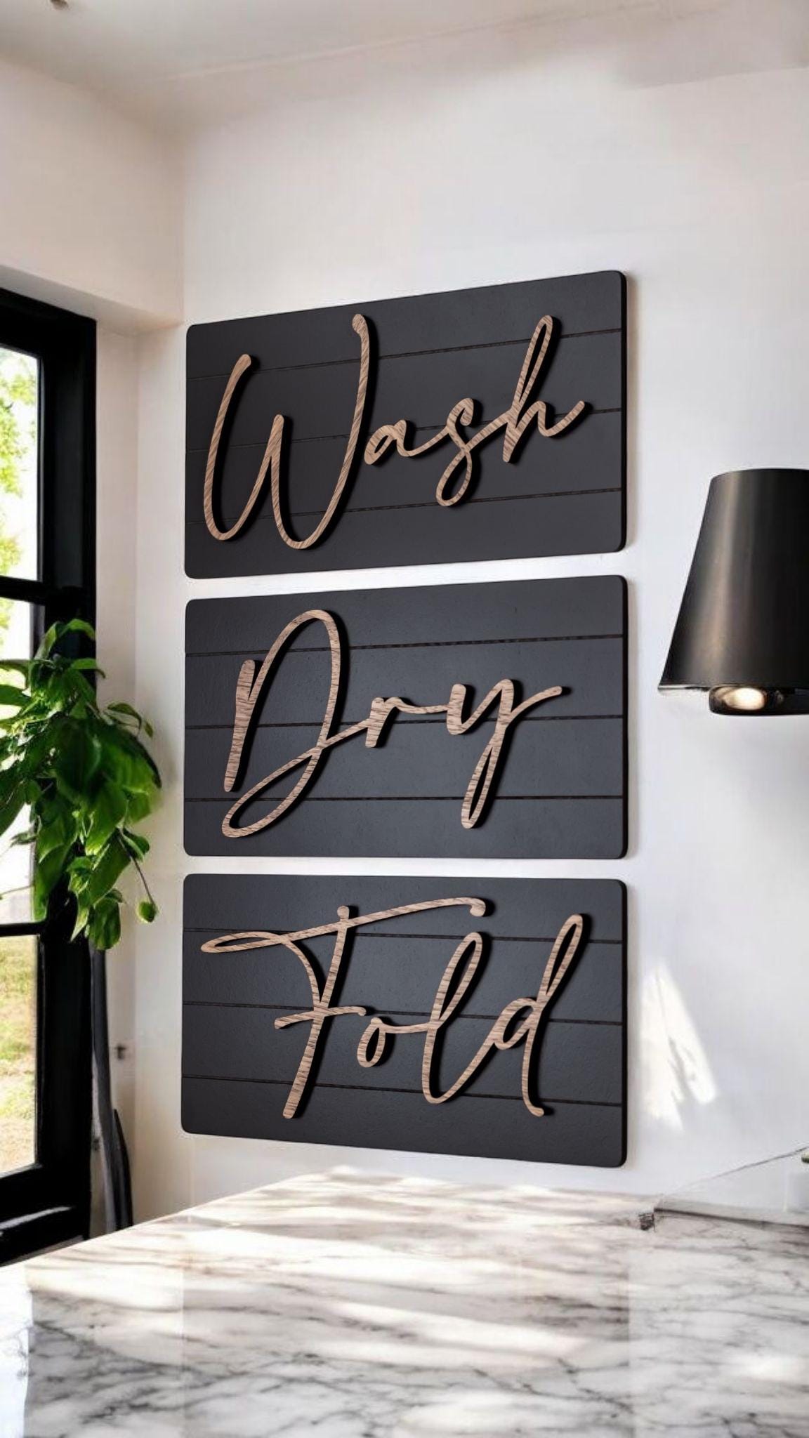 Three dark farmhouse wall signs reading Wash, Dry, Fold with wood-tone cursive lettering