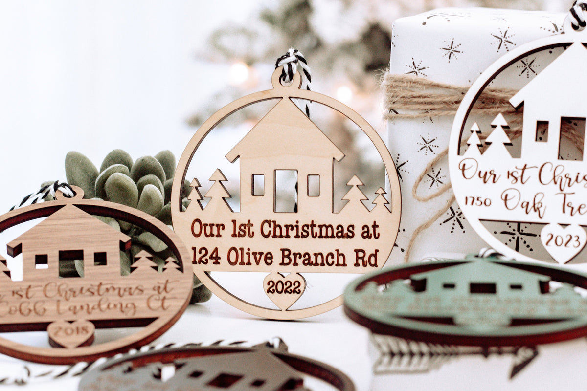 Round wooden Christmas keepsake ornament with house cutouts, hanging loop, and year