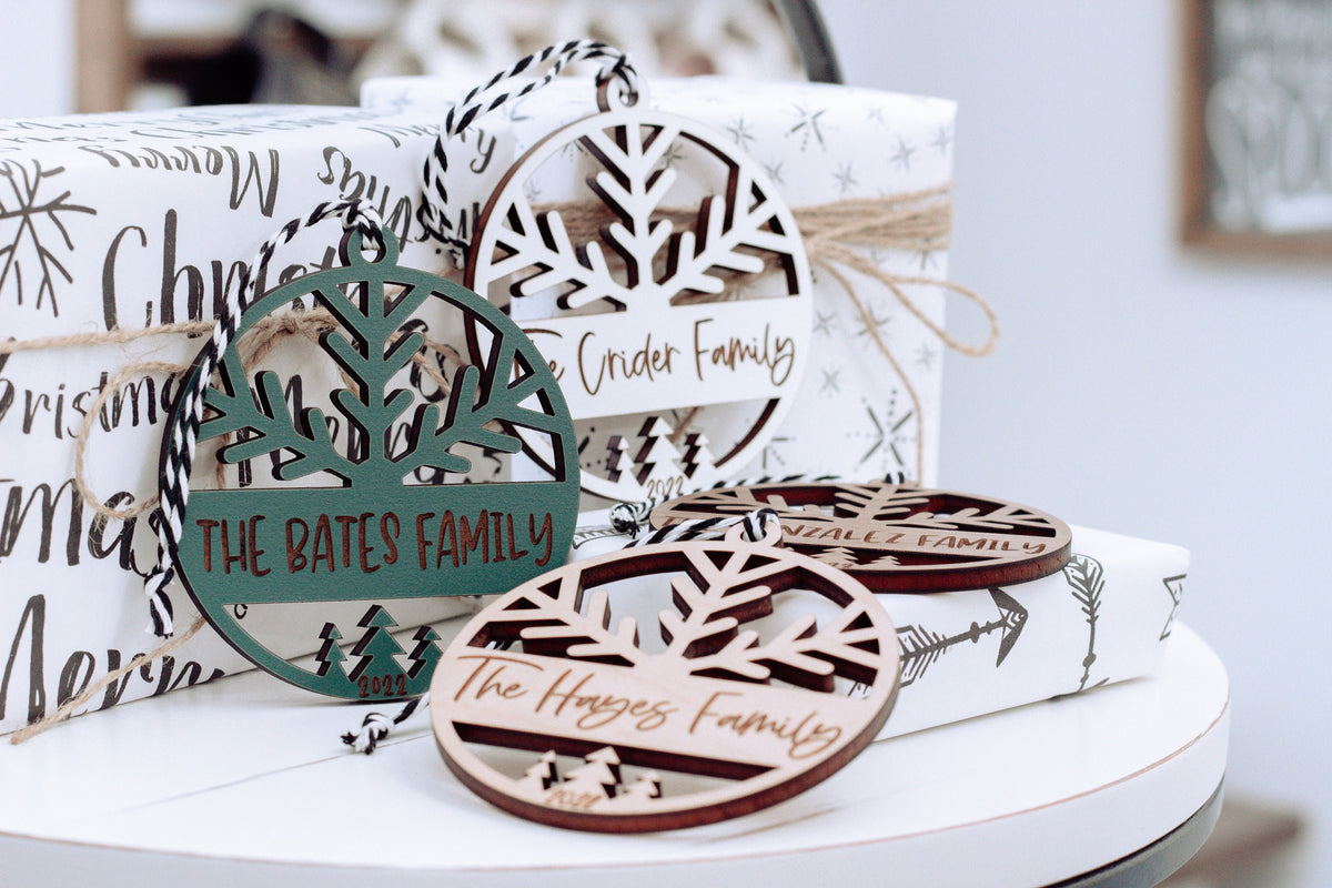 Set of engraved round family name Christmas ornaments with tree cutouts, gift boxes and ribbons