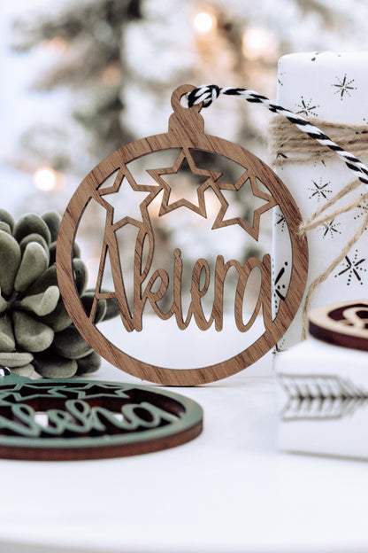Brown wooden round name ornament with star cutouts and arched engraved name