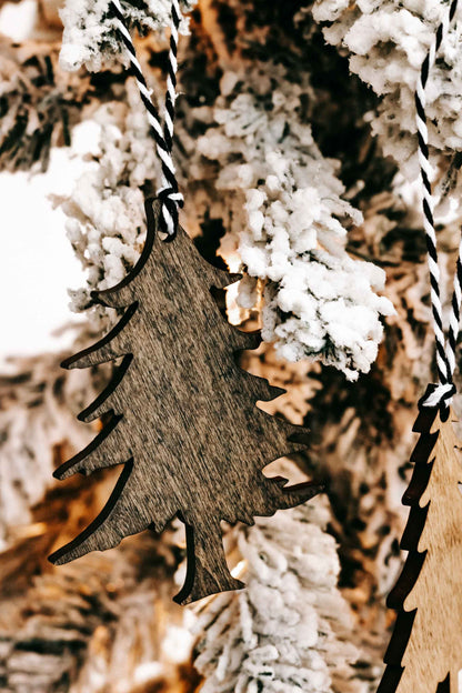 Brown wooden Christmas tree ornament with black-and-white striped hanging loop.