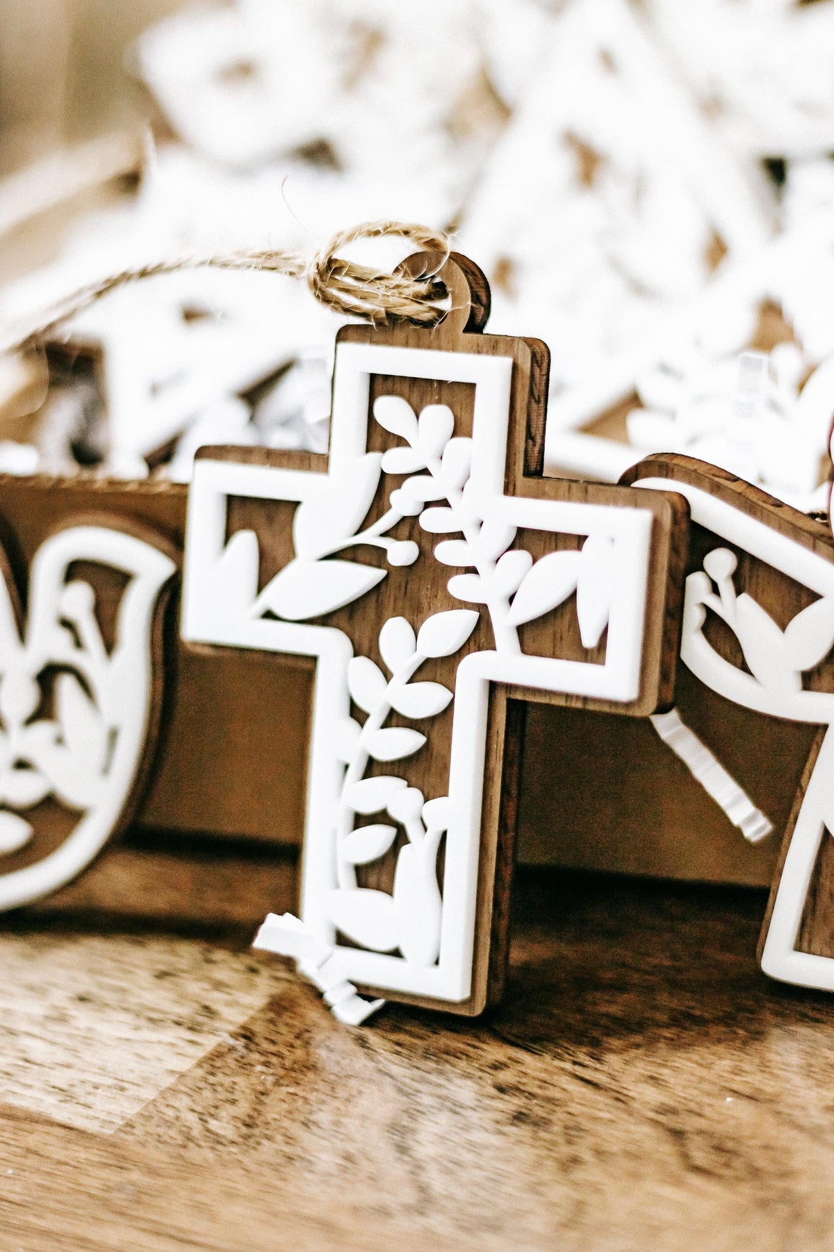 Close-up of white floral cutout cross Christmas ornament with hanging twine, set of 10