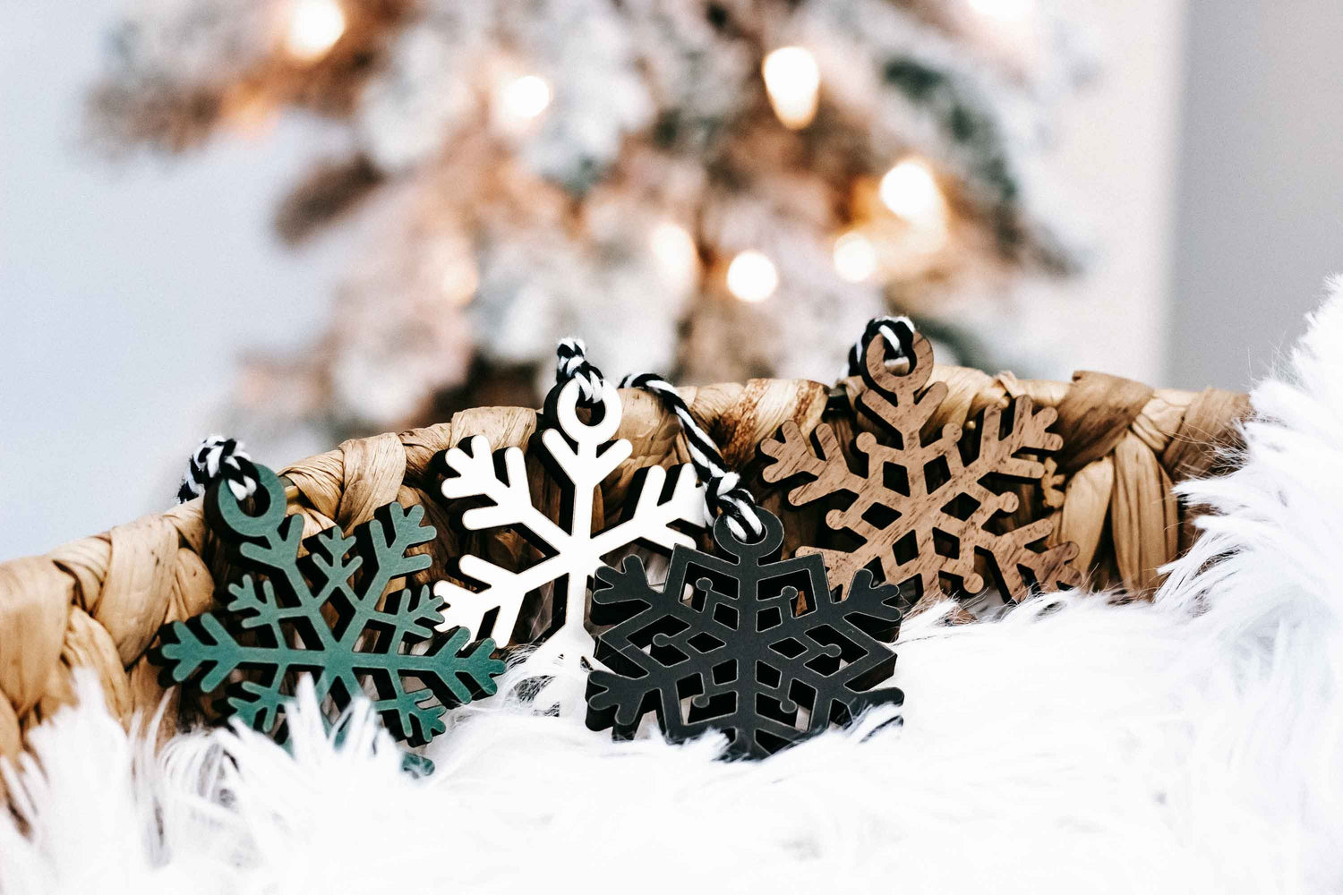Close-up of hanging snowflake ornaments in black, teal, tan, and white on faux fur