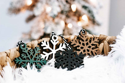 Close-up of hanging snowflake ornaments in black, teal, tan, and white on faux fur