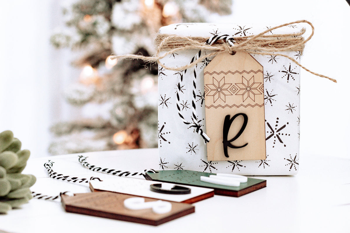 Hanging personalized wood stocking tag with Nordic pattern and letter R, tied with twine