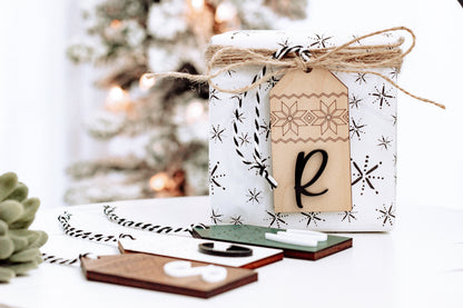 Hanging personalized wood stocking tag with Nordic pattern and letter R, tied with twine