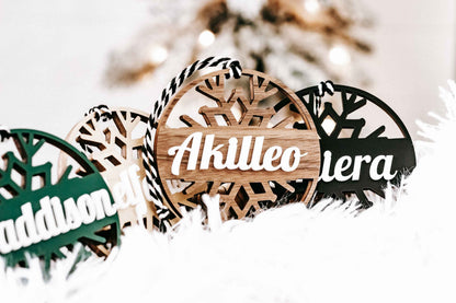 Personalized snowflake ornaments with tan and black round tags and white script names