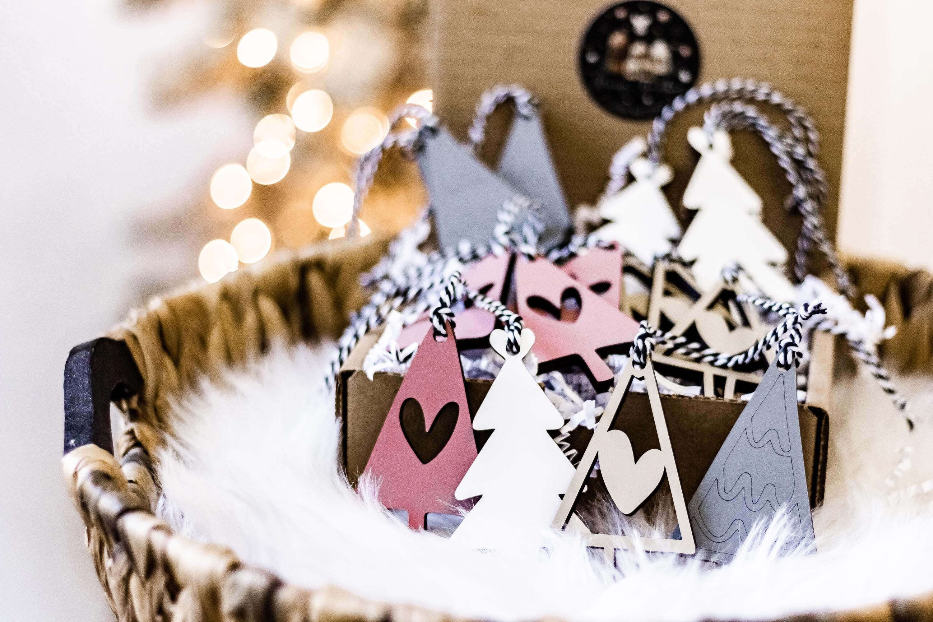 Wooden Christmas ornaments in blush, white, and gray with tree shapes and braided hangers