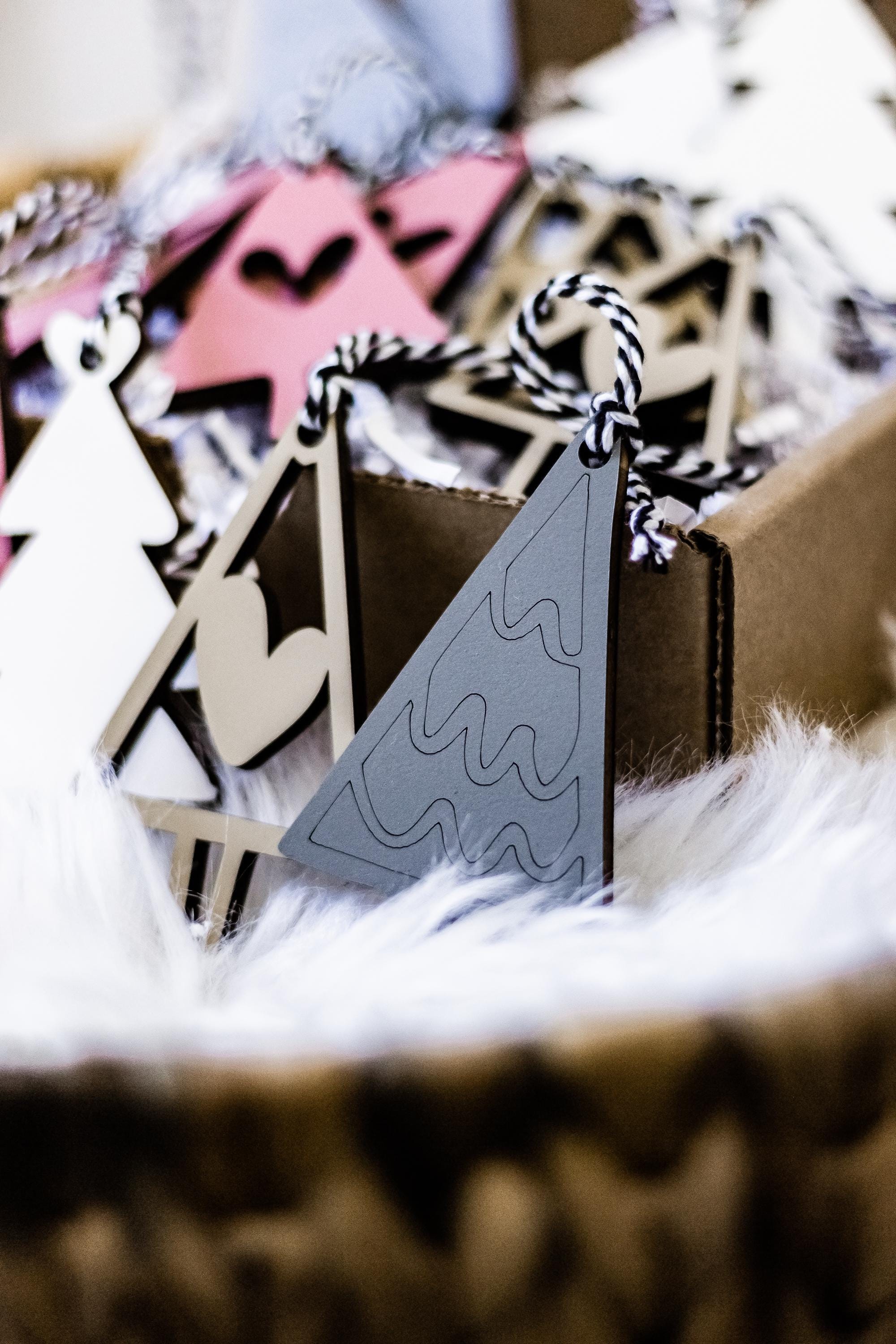 Close-up of wooden Christmas tree and tag ornaments in blush pink, white, and gray