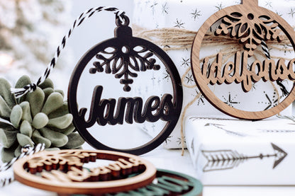 Round wooden name ornament with snowflake cutout and dark lettering on white