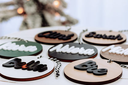 Assorted round wooden name ornaments with rope hangers and mixed black, white, and colored lettering
