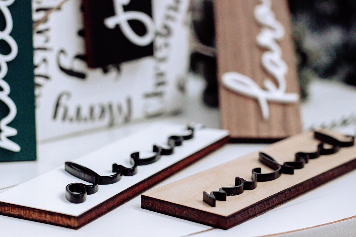 Personalized wooden stocking tags showing raised letter cutouts on dark and walnut boards