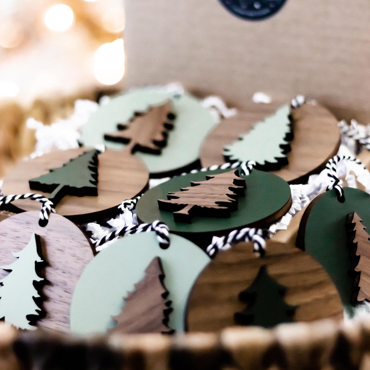 Wood and painted Christmas tree ornaments with striped hanging cords in the box