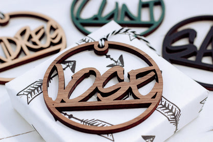 Brown wooden laser-cut custom name ornament with hanging loop and ribbon, round shape