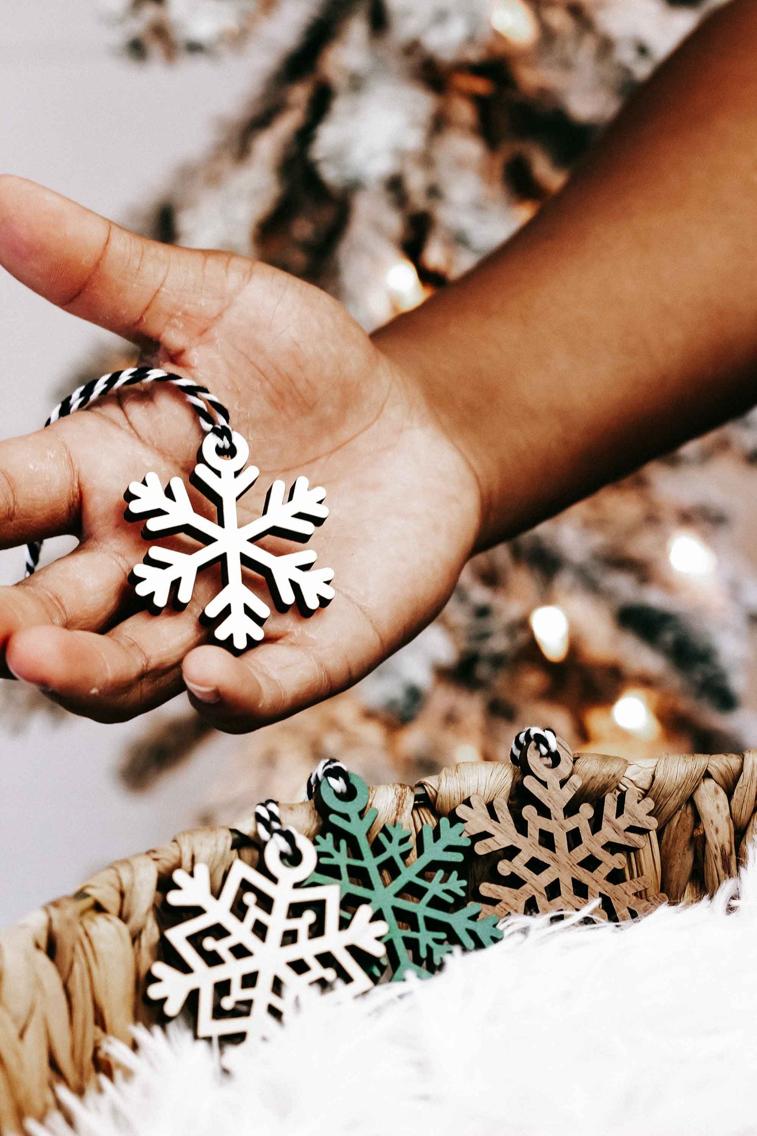 Snowflake wooden ornament held in hand, black and white cutout design with small loop