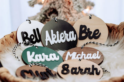 Round wooden name ornaments with rope hangers and teal, black, and tan lettering
