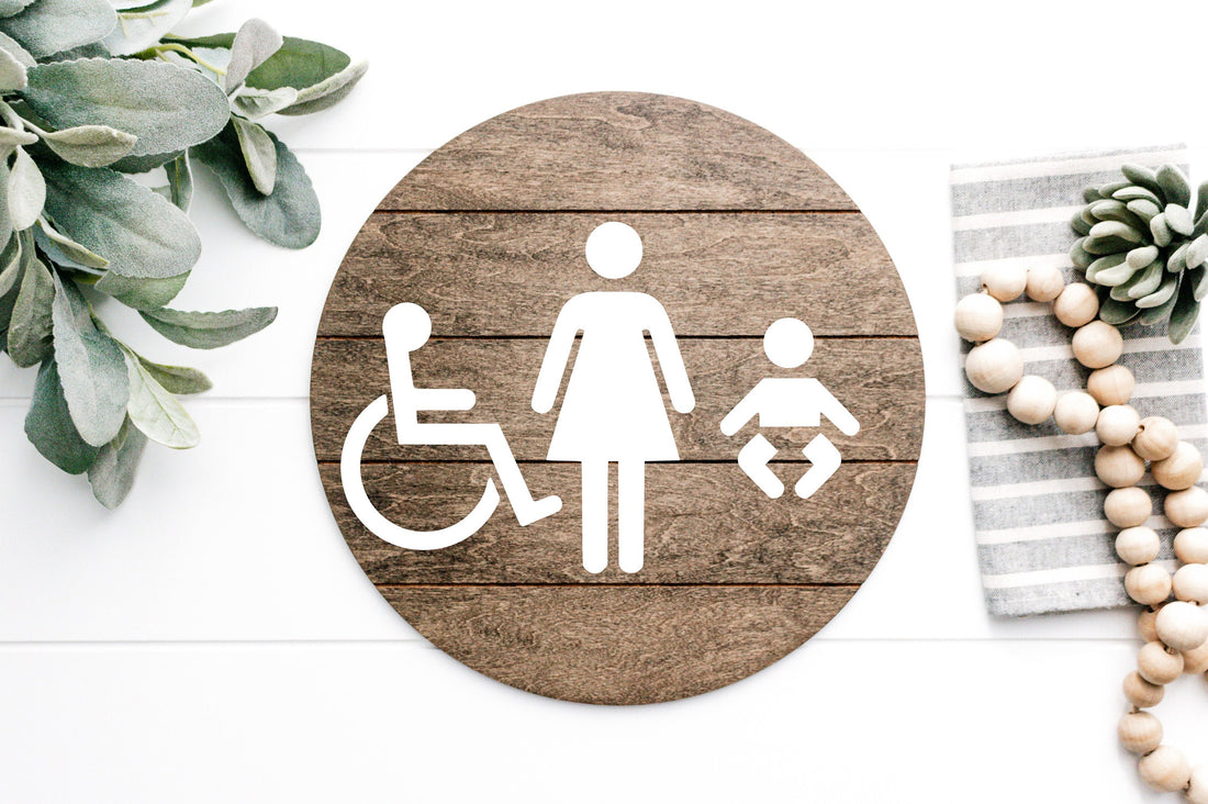 Accessibility restroom sign, round dark plaque with wheelchair and female figure icons