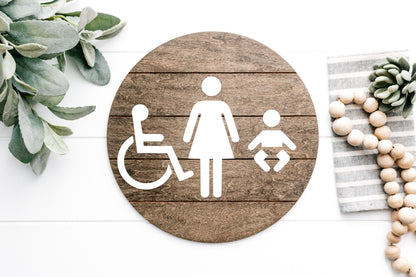 Accessibility restroom sign, round dark plaque with wheelchair and female figure icons