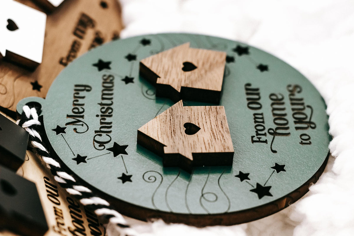 Close-up of green round wooden ornament with two dark house cutouts and heart icon