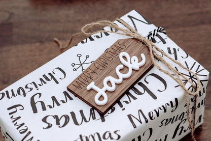 Wood gift tag with “Face” and Merry Christmas text, tied with twine