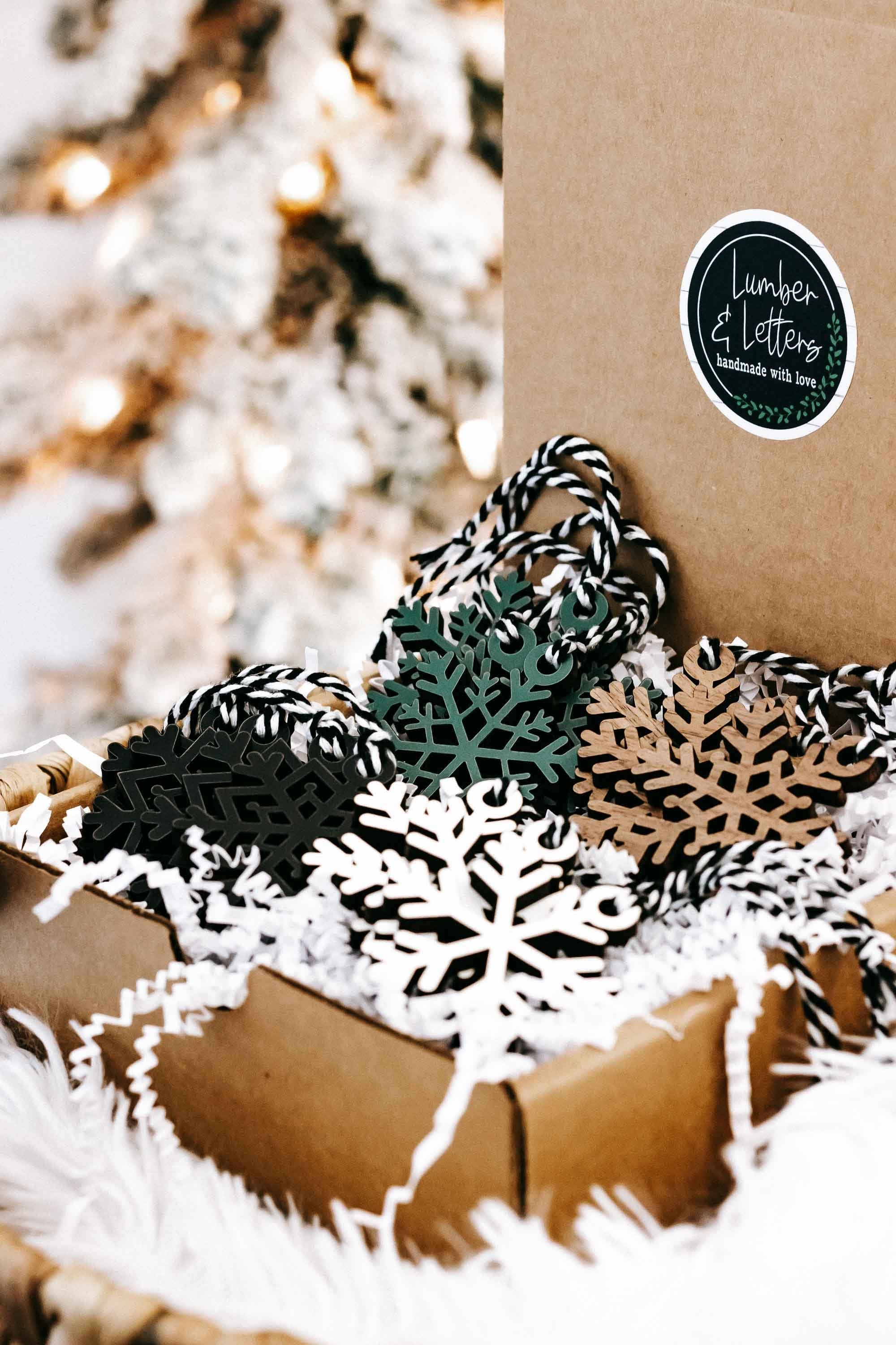 Snowflake ornament set with black, white, teal, and tan pieces near kraft packaging