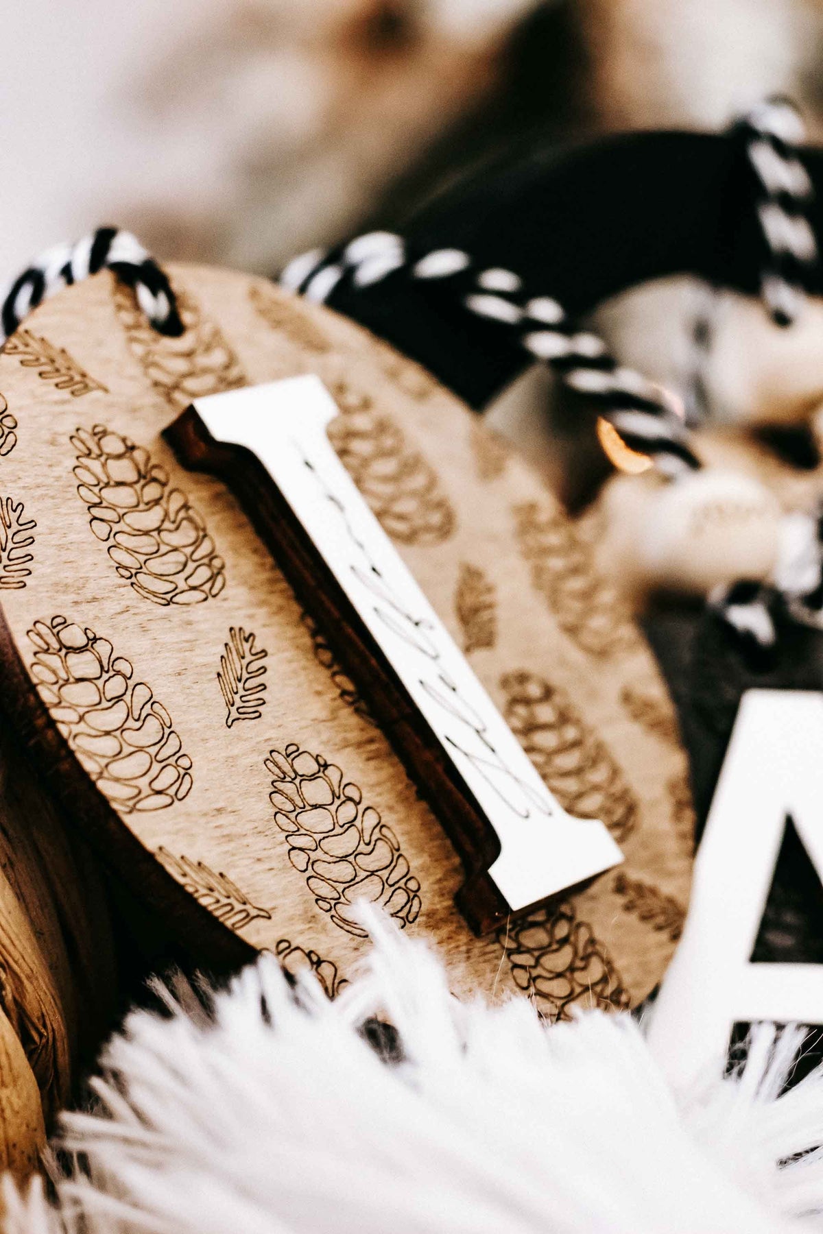 Round engraved pine cone ornament with letter I and zebra-striped hanging cord