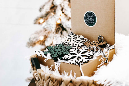 Snowflake wood Christmas ornaments in a box with white and dark green pieces