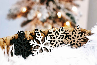 Set of snowflake wooden ornaments with black and white cutouts on twine and white faux fur