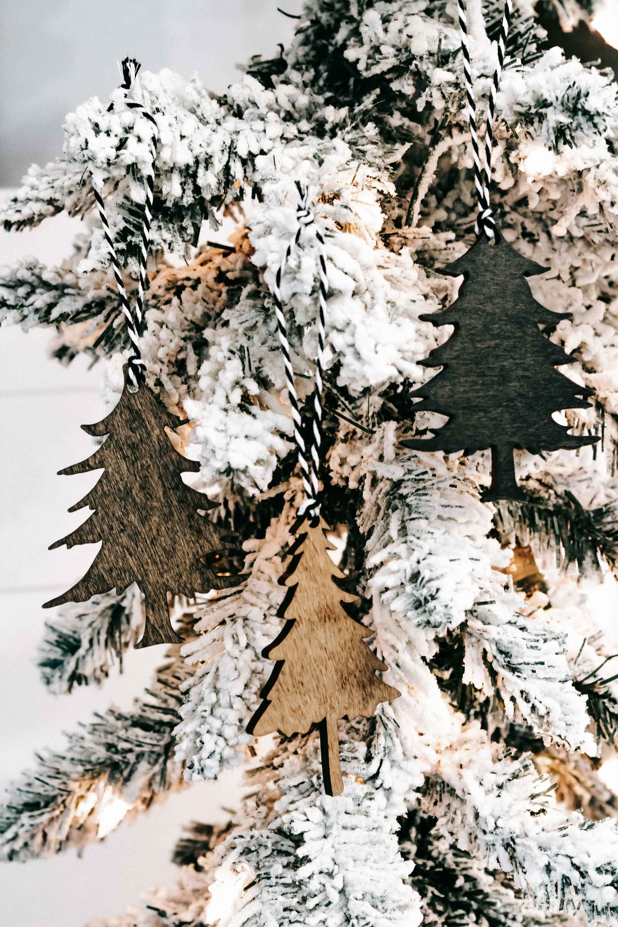 Hanging wooden Christmas tree ornaments in brown and dark green with snowy texture.