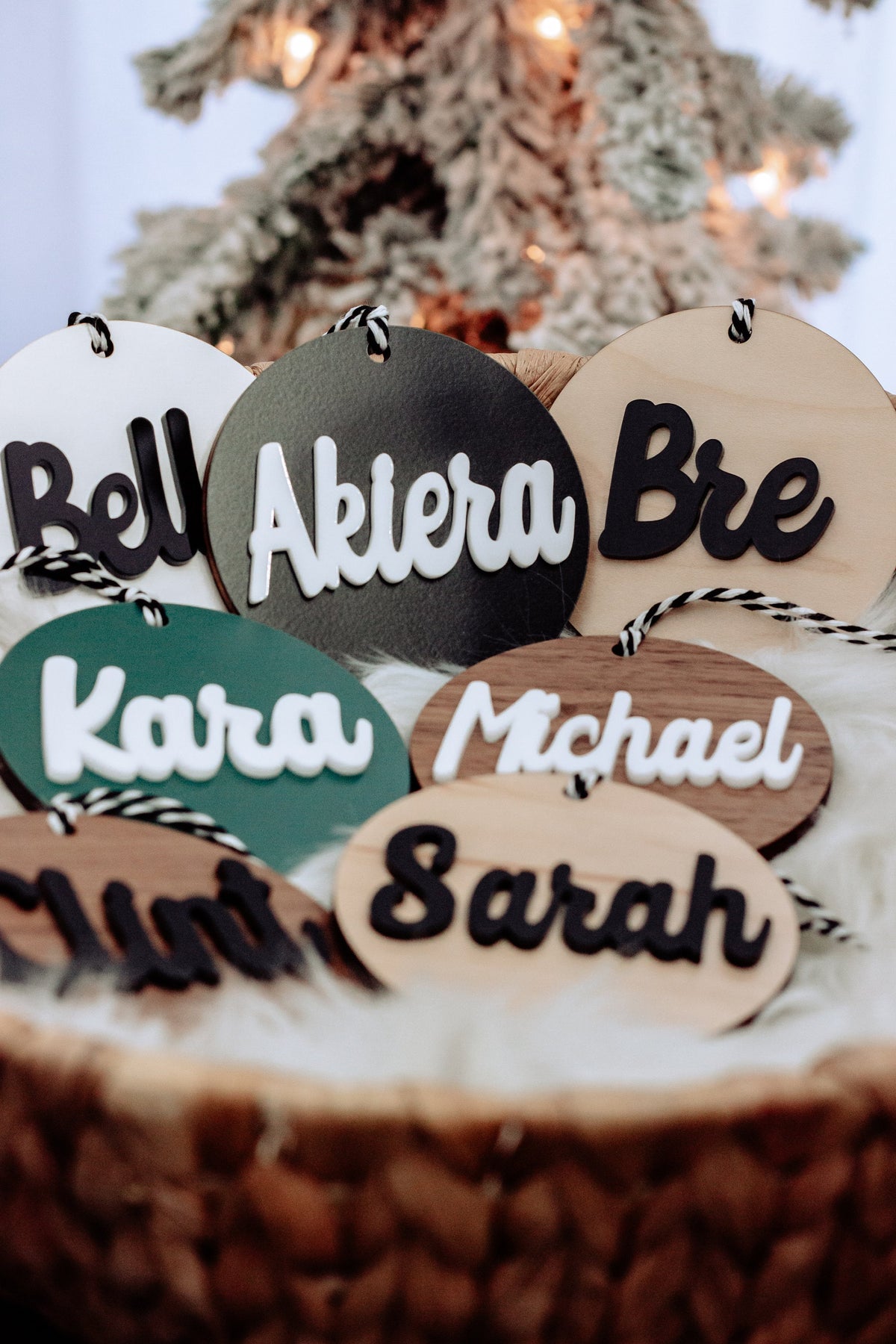 Set of round wooden name ornaments with rope hangers and mixed black, teal, and tan lettering