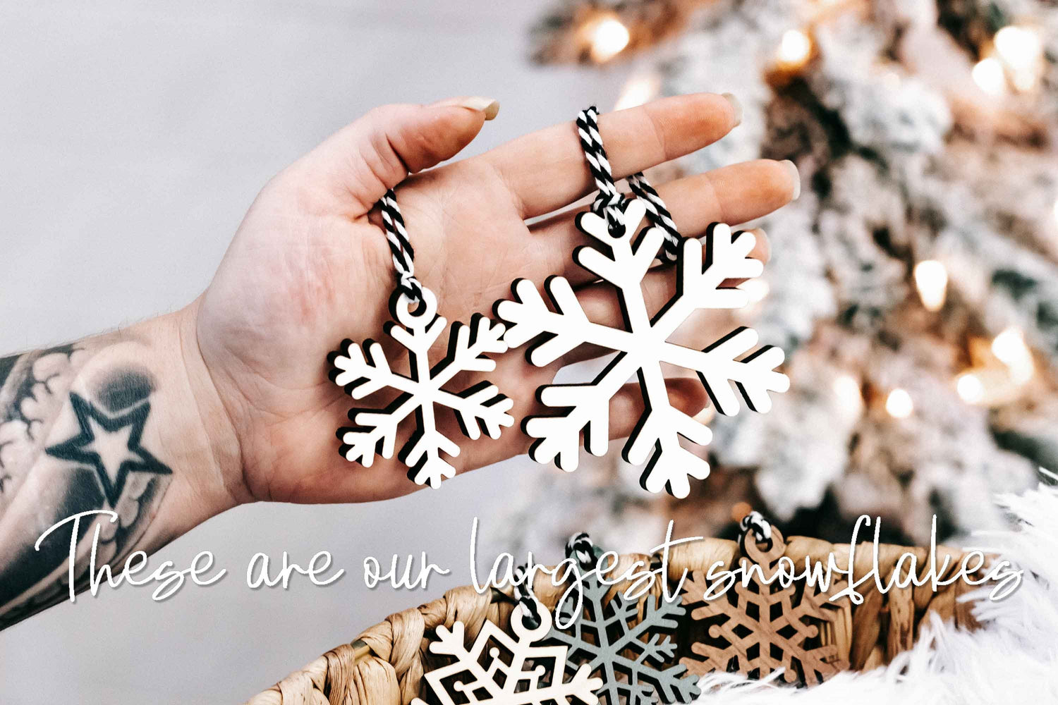 Hand holding wood snowflake ornament: white and dark layered cutout with braided string