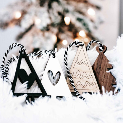 Close view of boho Christmas tree ornaments in black, white, and wood with striped string hangers