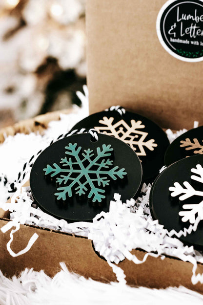 Set of 8 black wooden snowflake ornaments with white, green, and gold snowflake prints