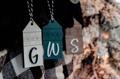 Close-up of personalized stocking tags with letters G, W, and S in Nordic patterns