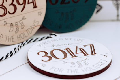 Round personalized home holiday ornament with “30114” in orange on white wood.