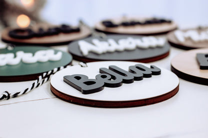 Single round wooden ornament with rope hanger, white face and bold black letter text