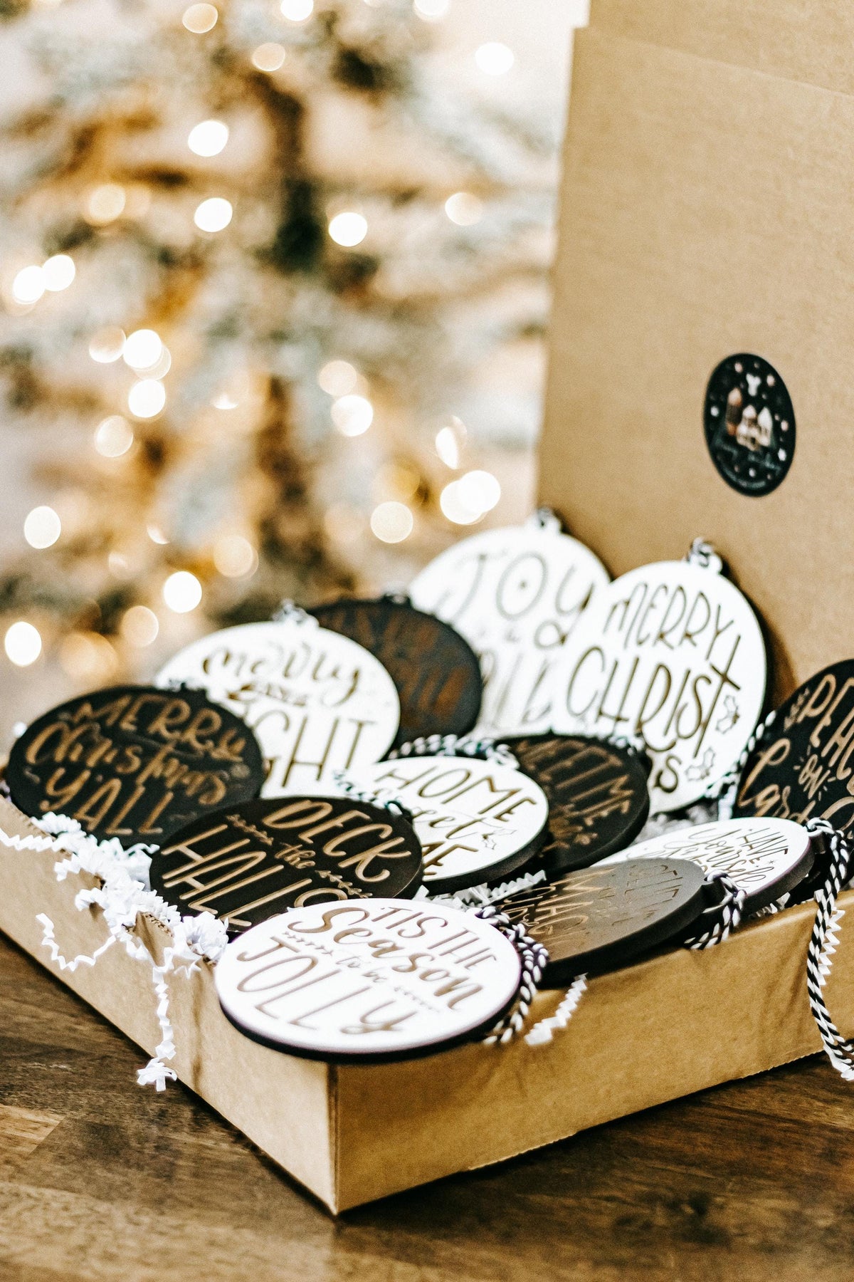 Engraved Christmas ornament set in a gift box, black and white discs with gold lettering.