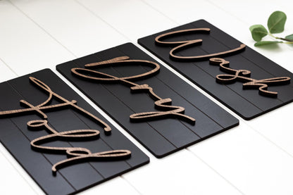 Angled view of three dark wall sign panels with cursive Wash, Dry, Fold lettering