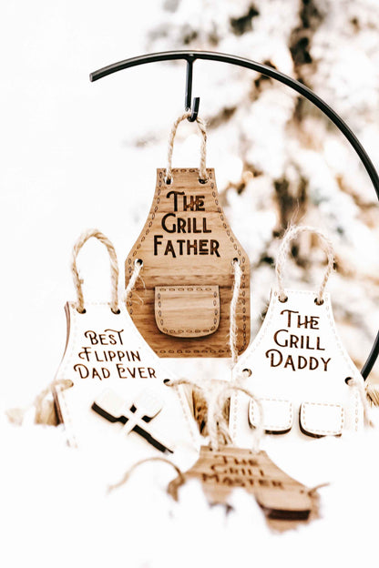 Wood grill father-themed ornament set on hanging twine: “The Grill Father,” “Best Flippin’ Dad Ever,” and “The Grill Daddy.”