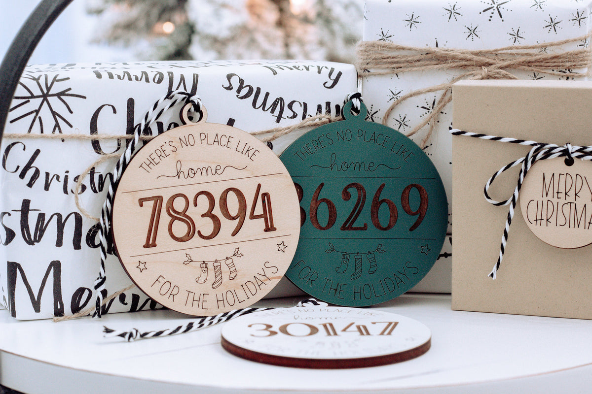 Round personalized home holiday ornaments in white, teal, and brown with zip codes 18394 and 66269.