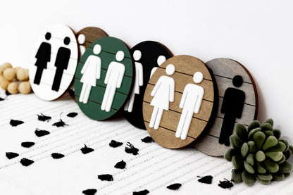 3D restroom sign set featuring restroom icons on round wood and green plaques