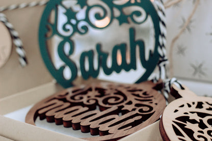 Close-up of green laser-cut name ornament with scrollwork in gift box