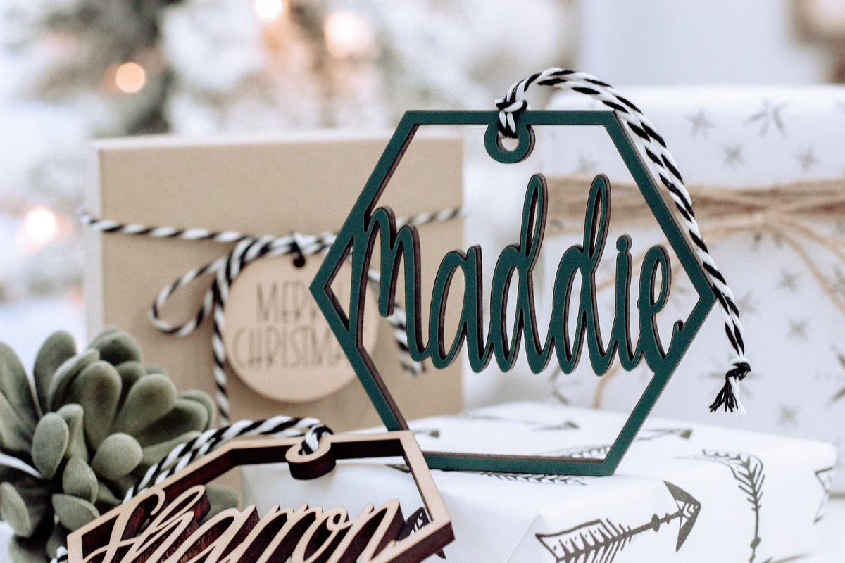 Wooden hex name ornament with teal cursive “Madalie” engraving, twine loop, gift box