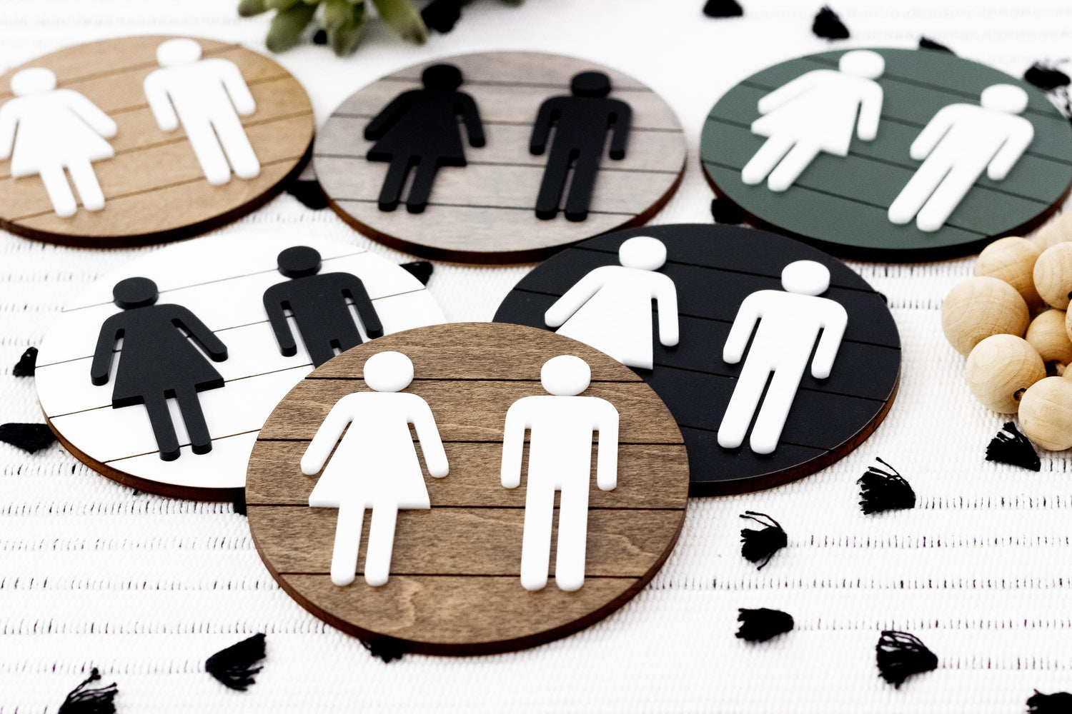 Assorted directional restroom signs with female and male icons on round dark and wood backgrounds