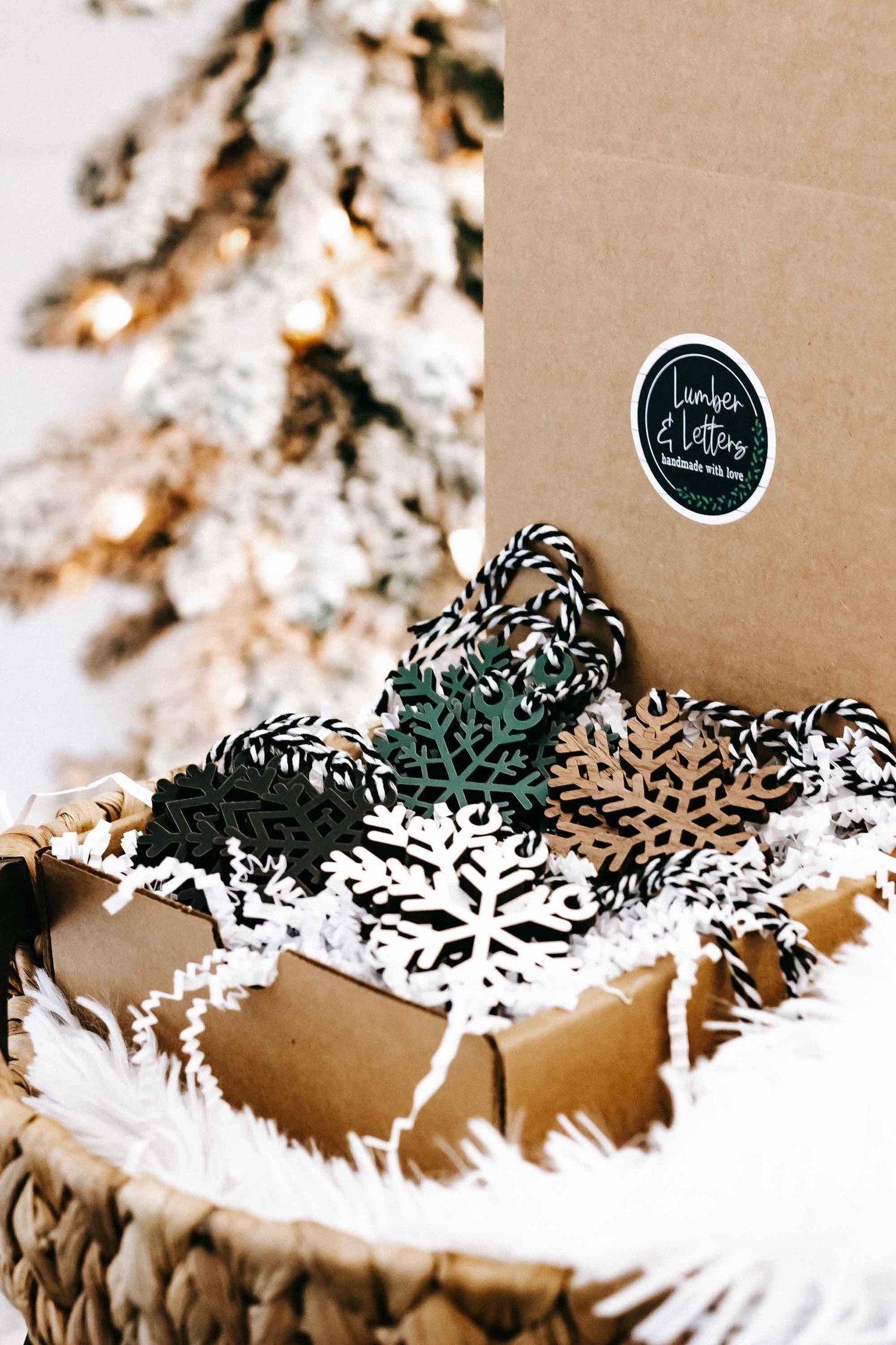 Snowflake Christmas ornaments on white faux fur with kraft packaging and twine hangers